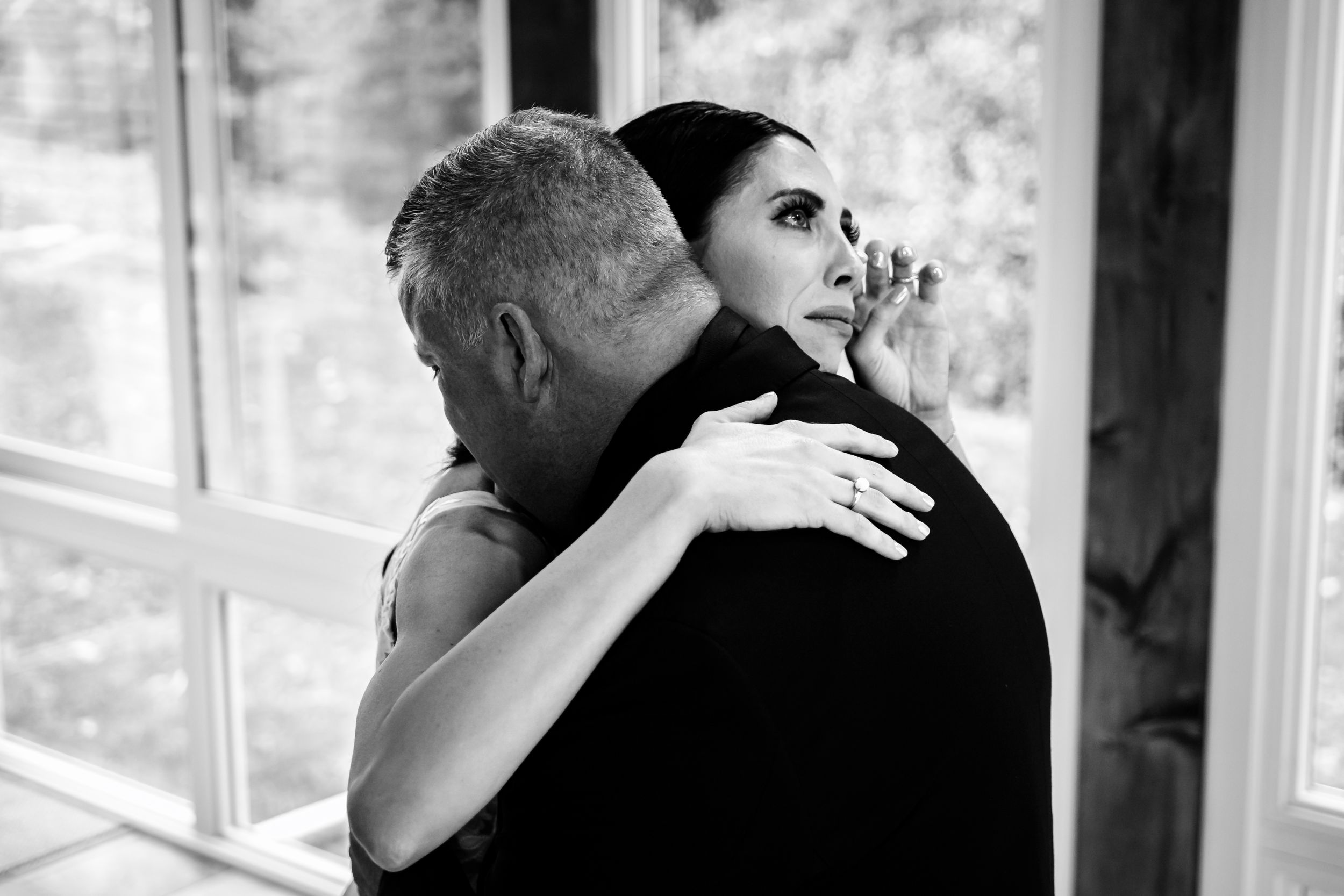 Emotional first look moment between couple in rustic wood-paneled room.