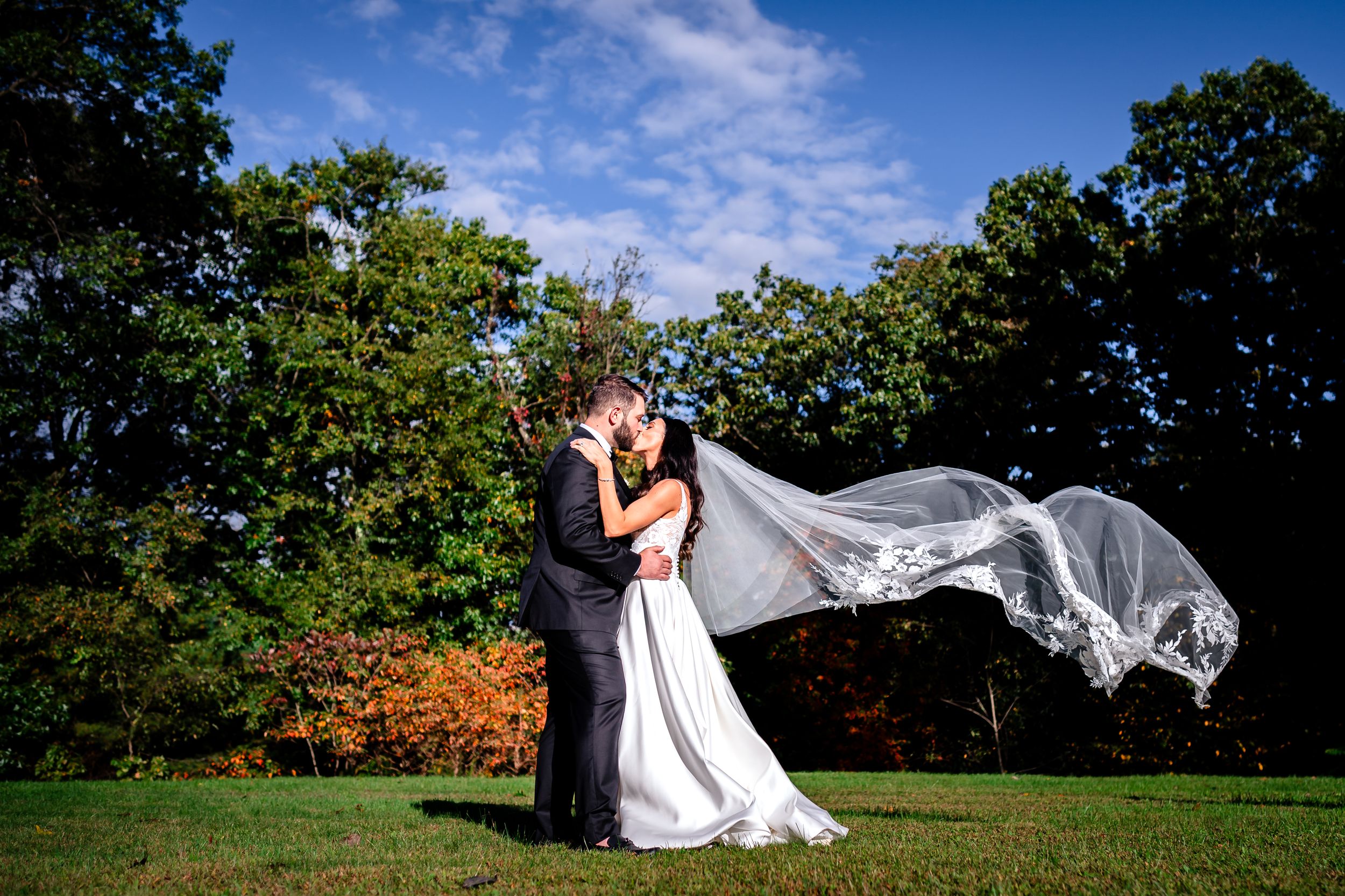 Flowing white wedding veil catches breeze during outdoor photo session.