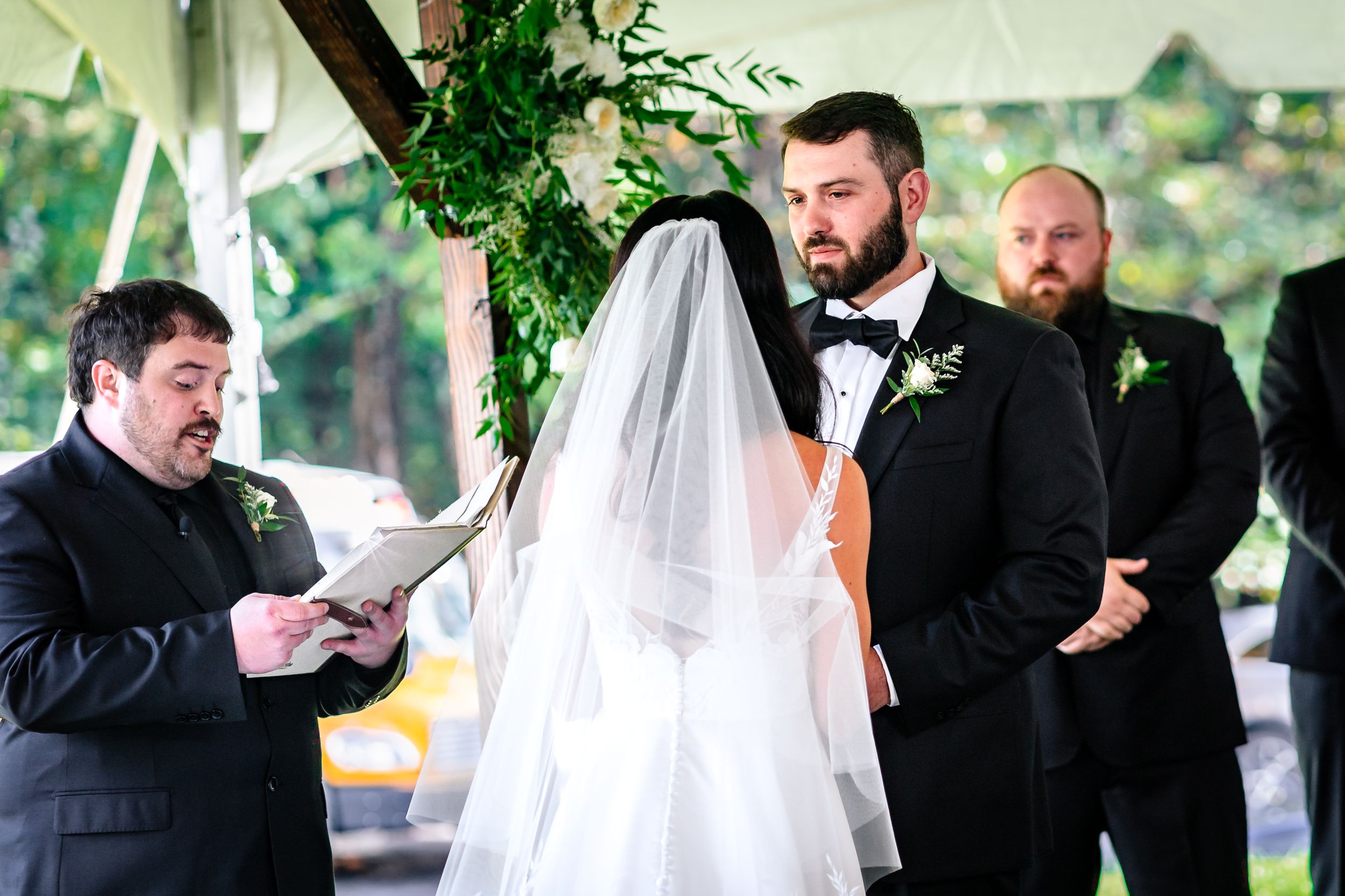 Wedding party members share emotional moments during an outdoor ceremony.