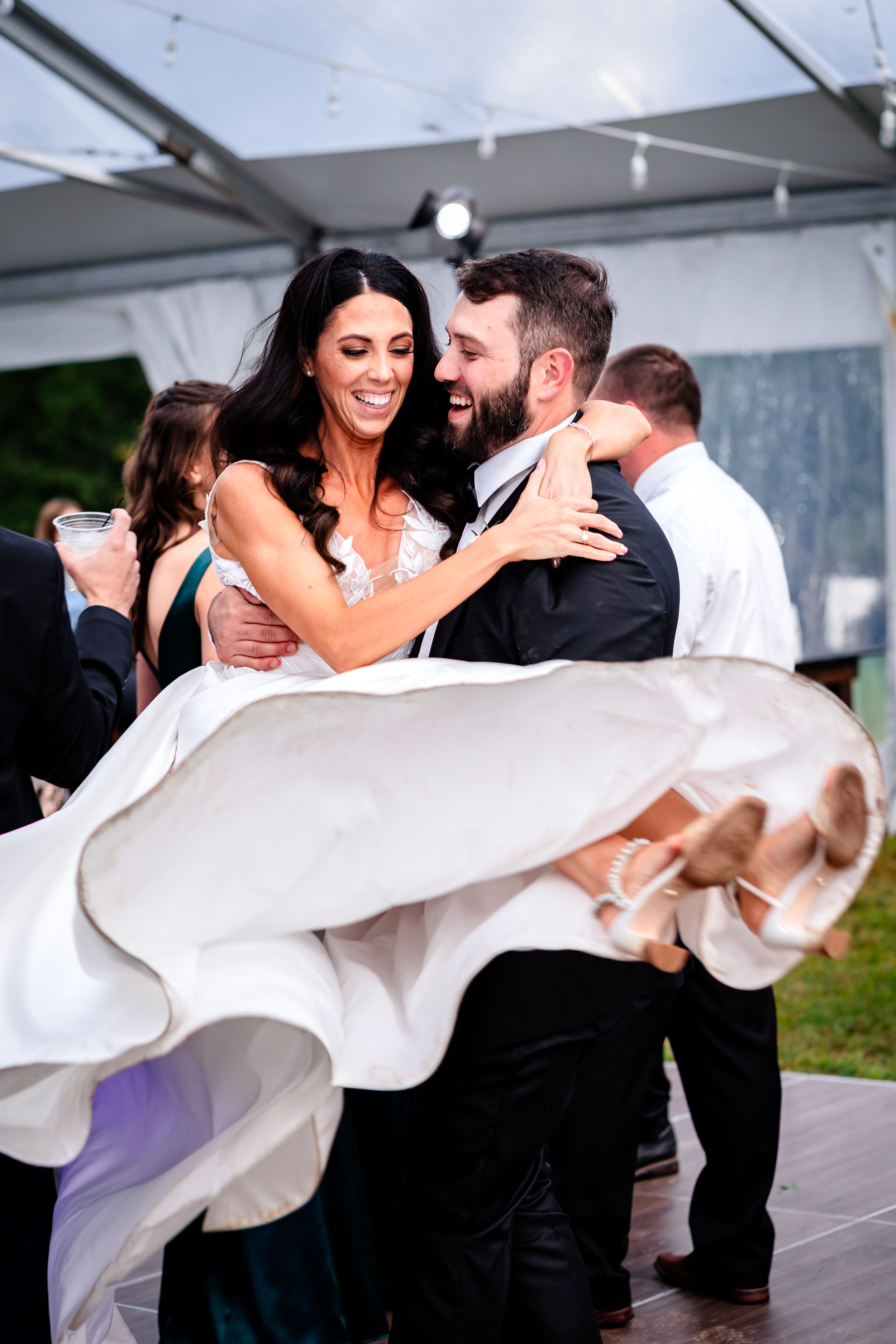 Dynamic dance moves captured during wedding reception under white tent.