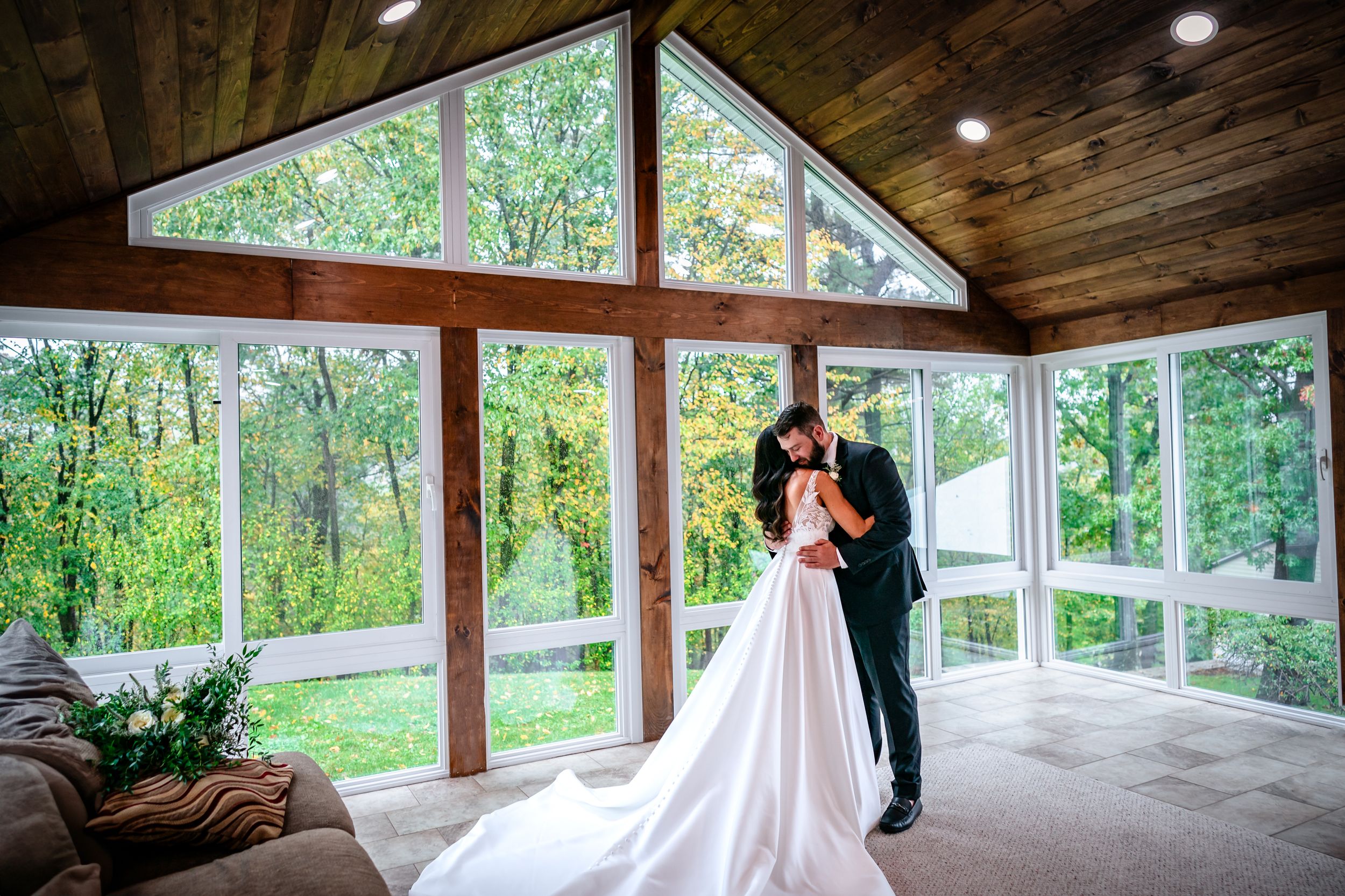 Wedding ceremony space with wooden beams and floor-to-ceiling windows overlooking nature.