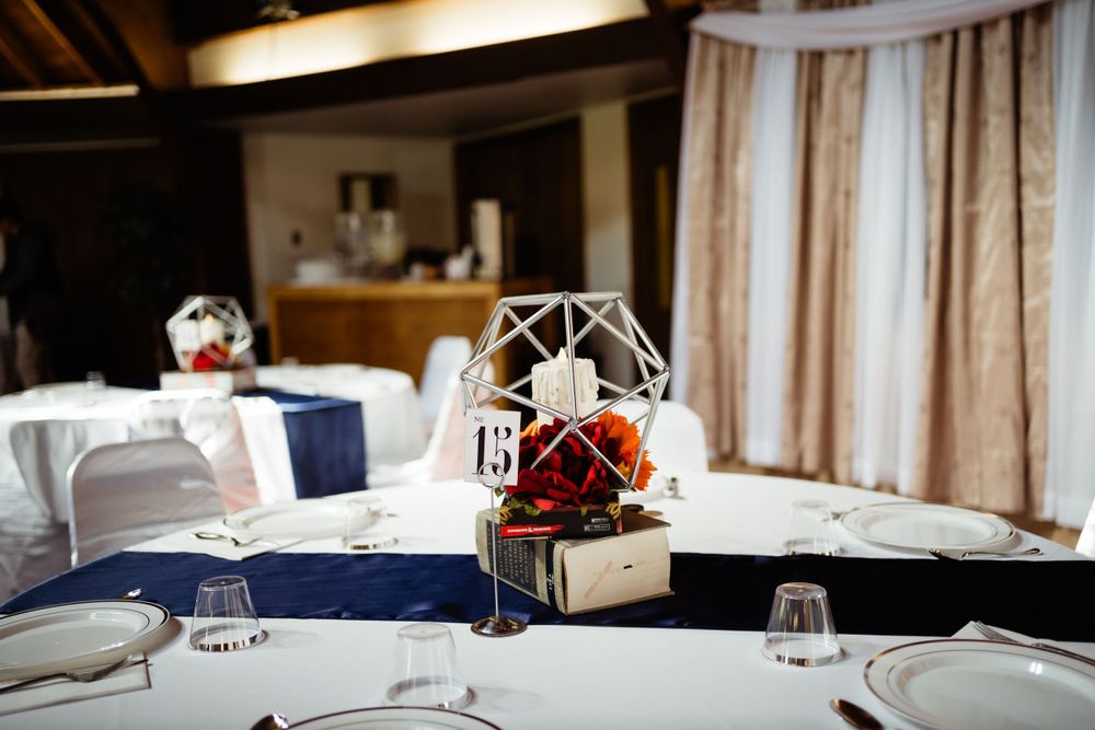 Wedding reception table setting with geometric centerpiece and navy blue accents.