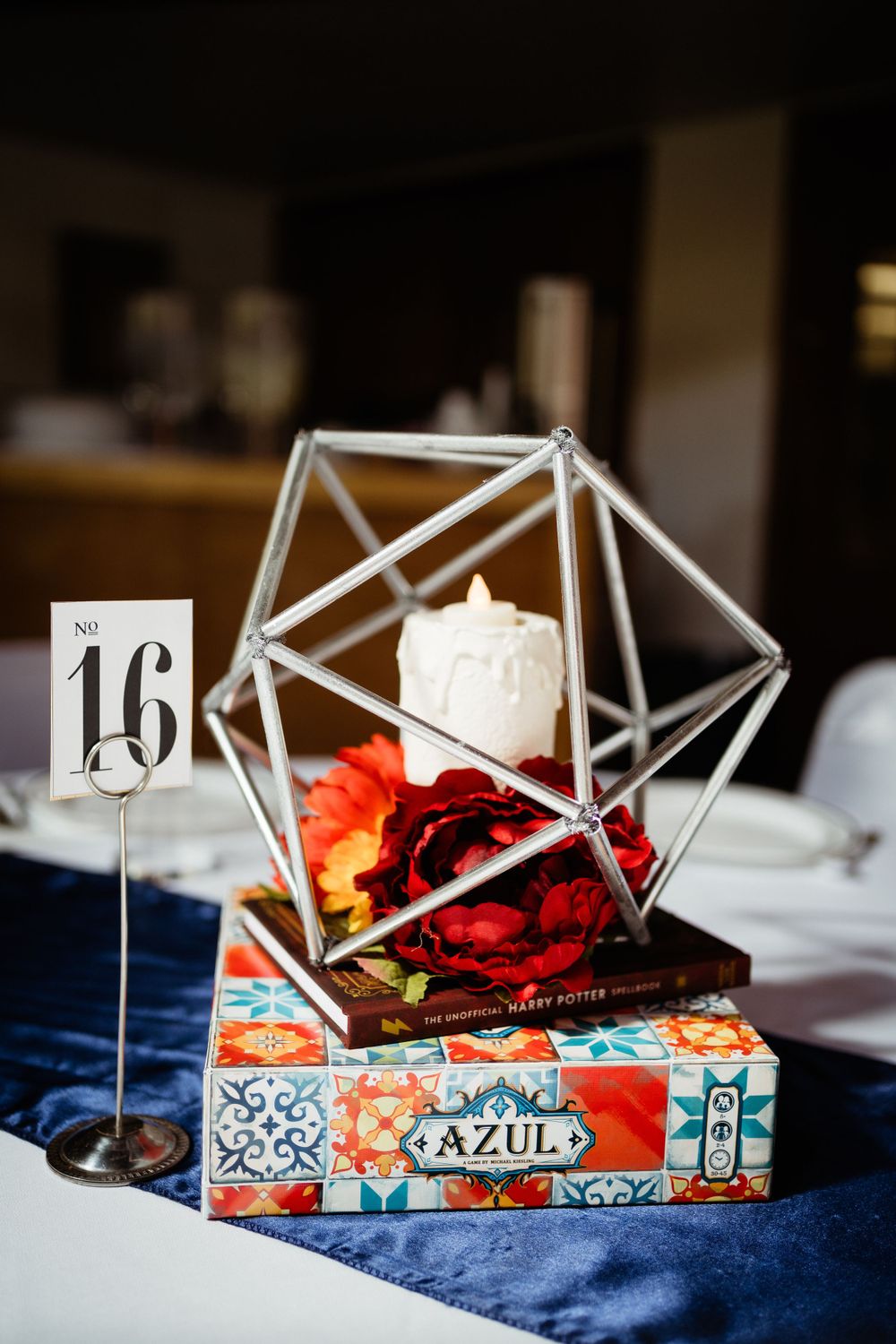 Modern geometric terrarium centerpiece with red rose and Azul board game.