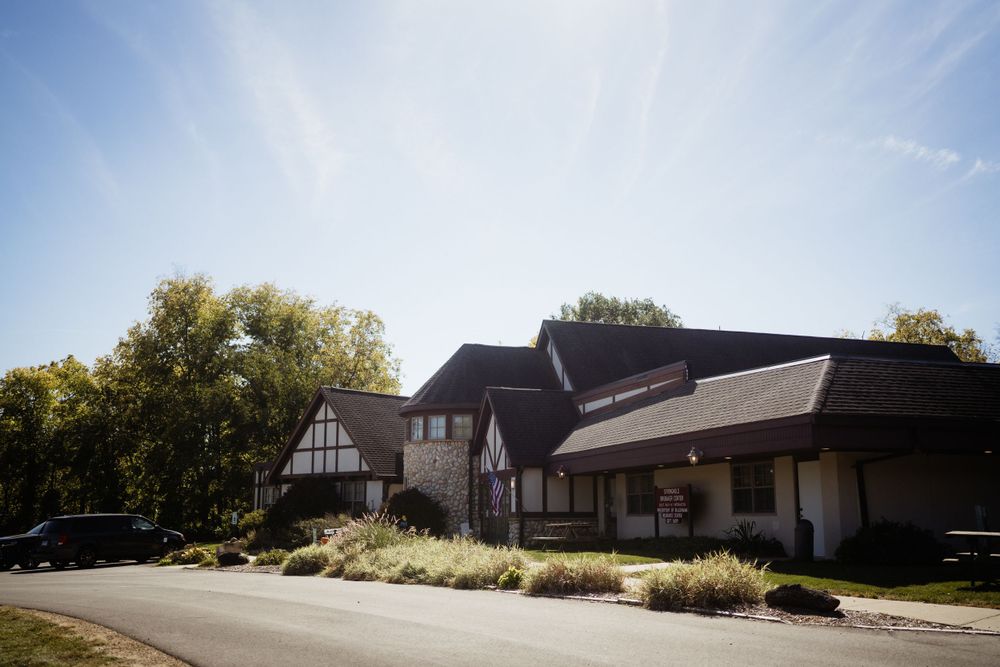 Exterior view of a Tudor-style building with dark trim and landscaping on a sunny day.