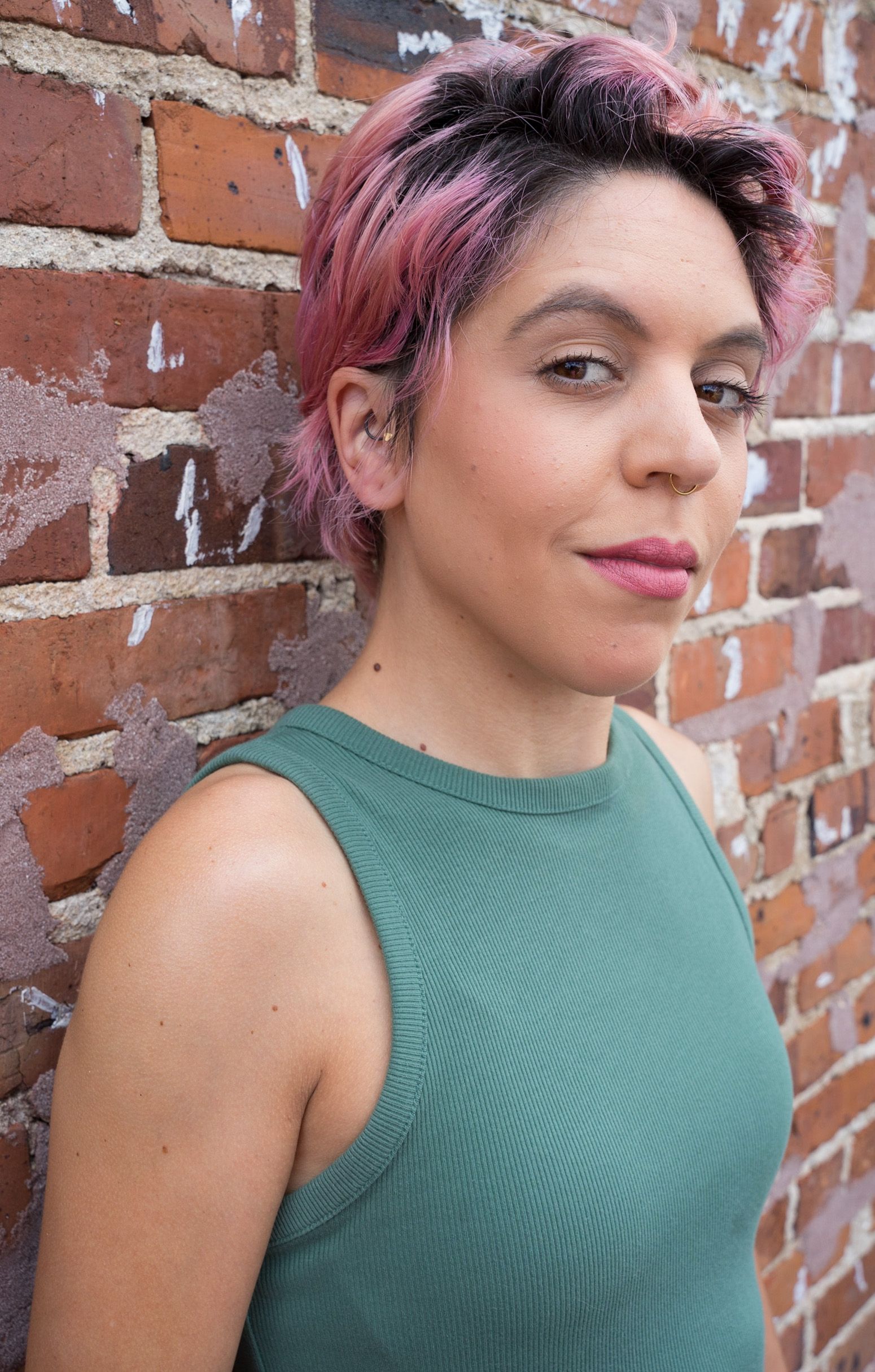 Portrait against weathered brick wall showcasing casual summer style.