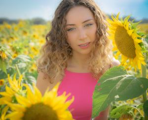 Sunlit portrait session in blooming sunflower field with warm summer lighting.