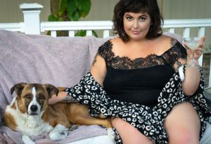 Person in floral dress relaxing on porch with dogs lounging nearby.