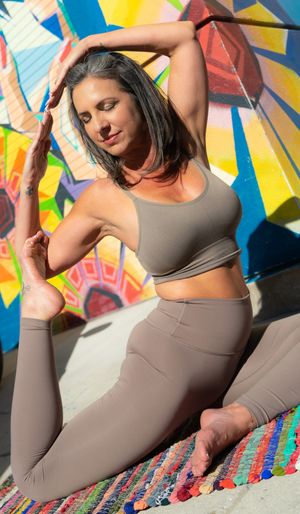 Athletic pose against vibrant graffiti wall in matching gray workout set.