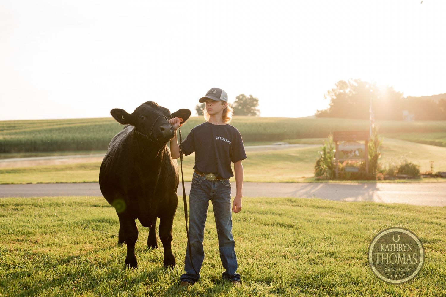 Handler and black show steer standing together in golden evening light on pasture.