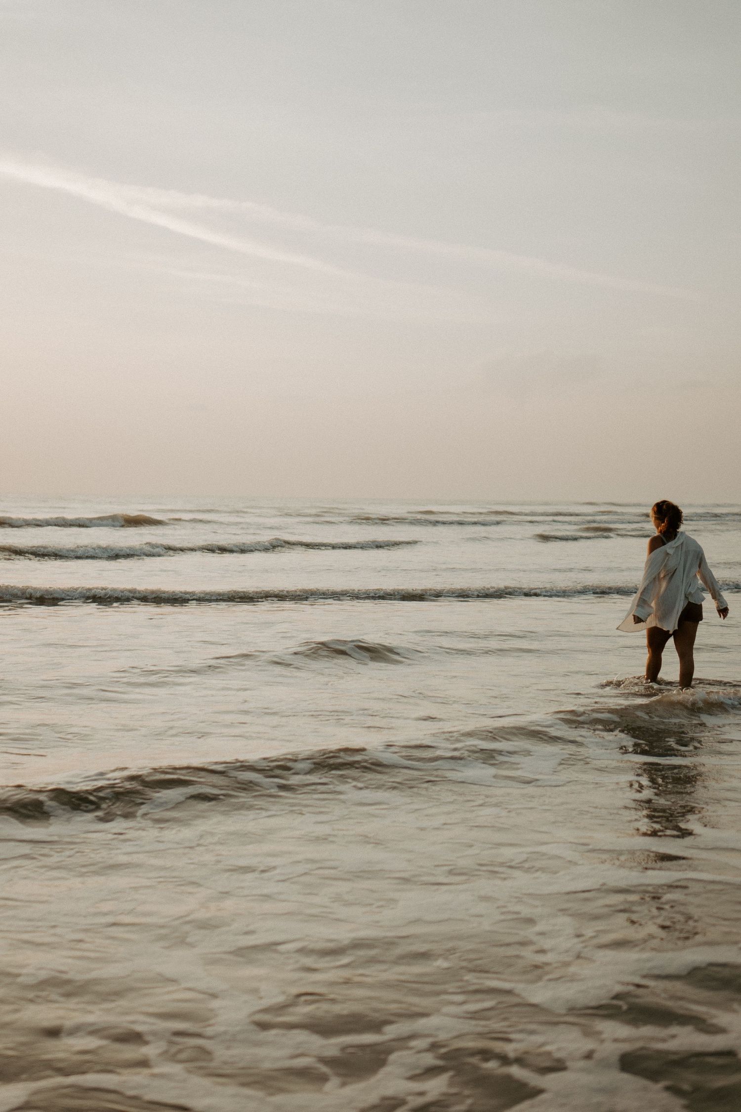 Young woman walking into the Ocean water in New Smyrna Beach at sunrise