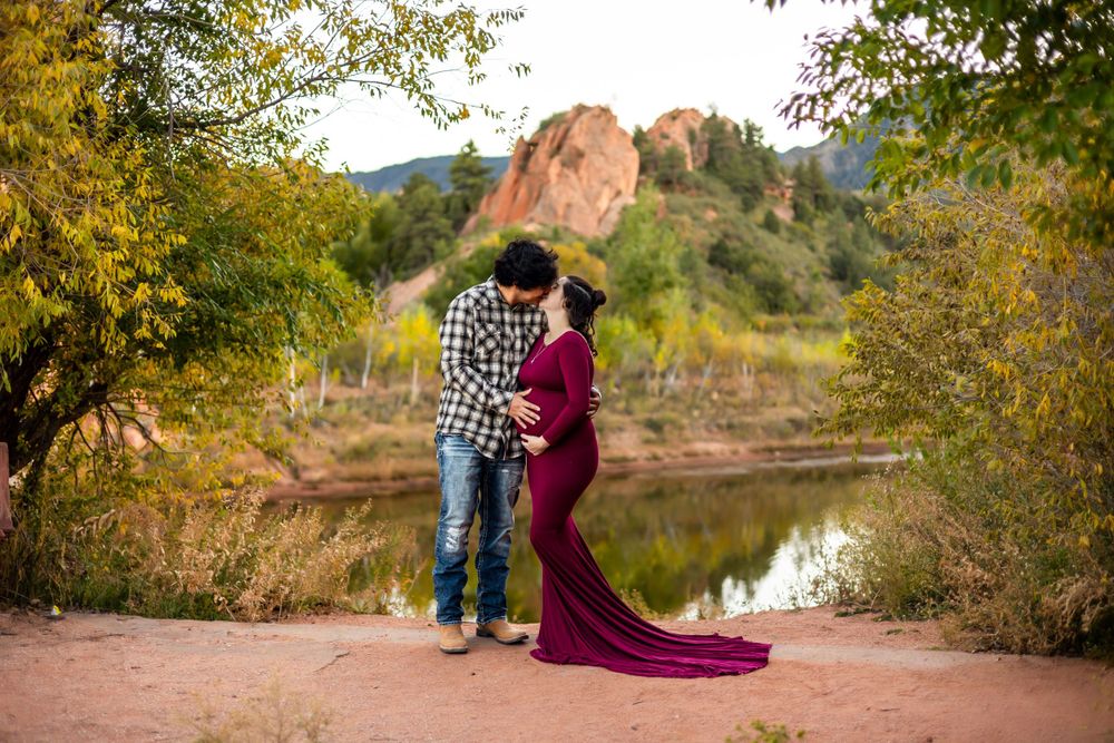 A romantic couple's maternity photo at sunset with red rocks and autumn foliage.