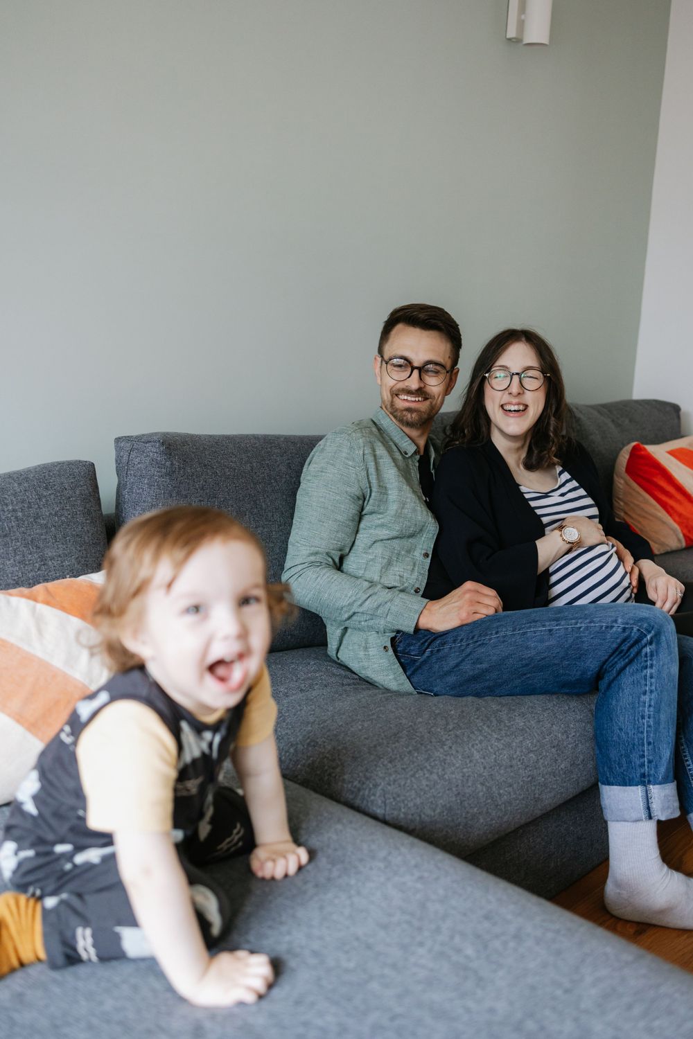 Family relaxing together on a comfortable gray sectional couch in a bright living room interior.