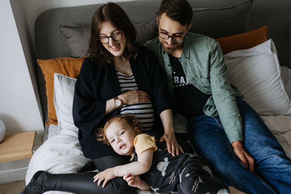 A family relaxes together on a couch with their black dog, creating a cozy moment at home.