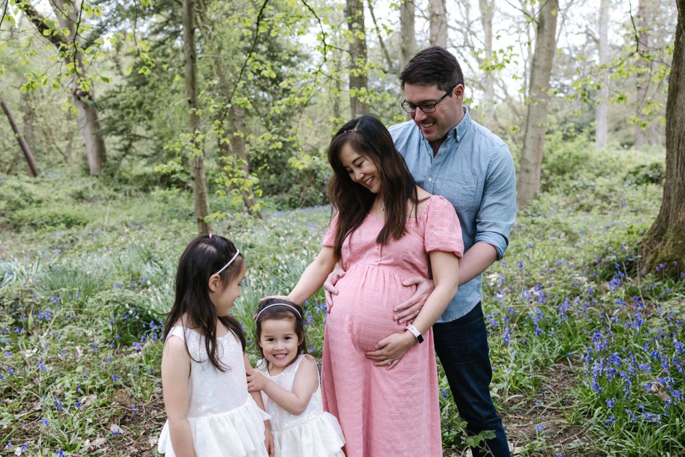 A family shares a tender moment together in a spring forest surrounded by blooming bluebells.