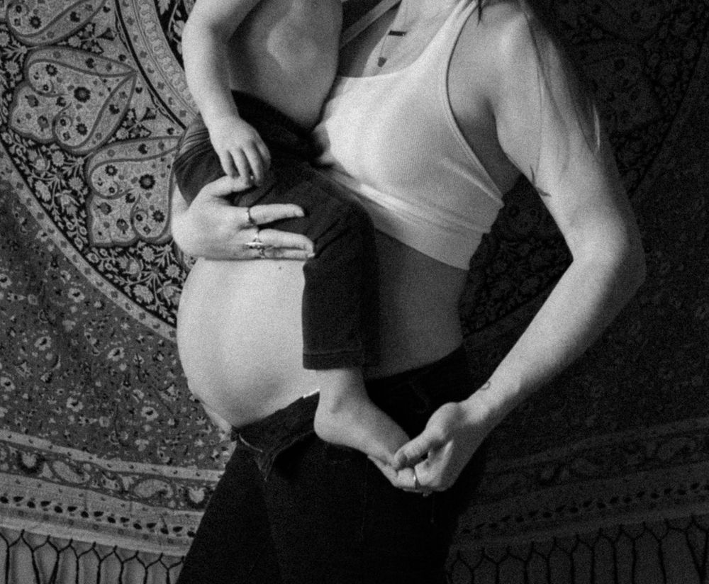 iowa midwest maternity and family photography. cropped image of a pregnant woman with her older child rested on her belly. black and white