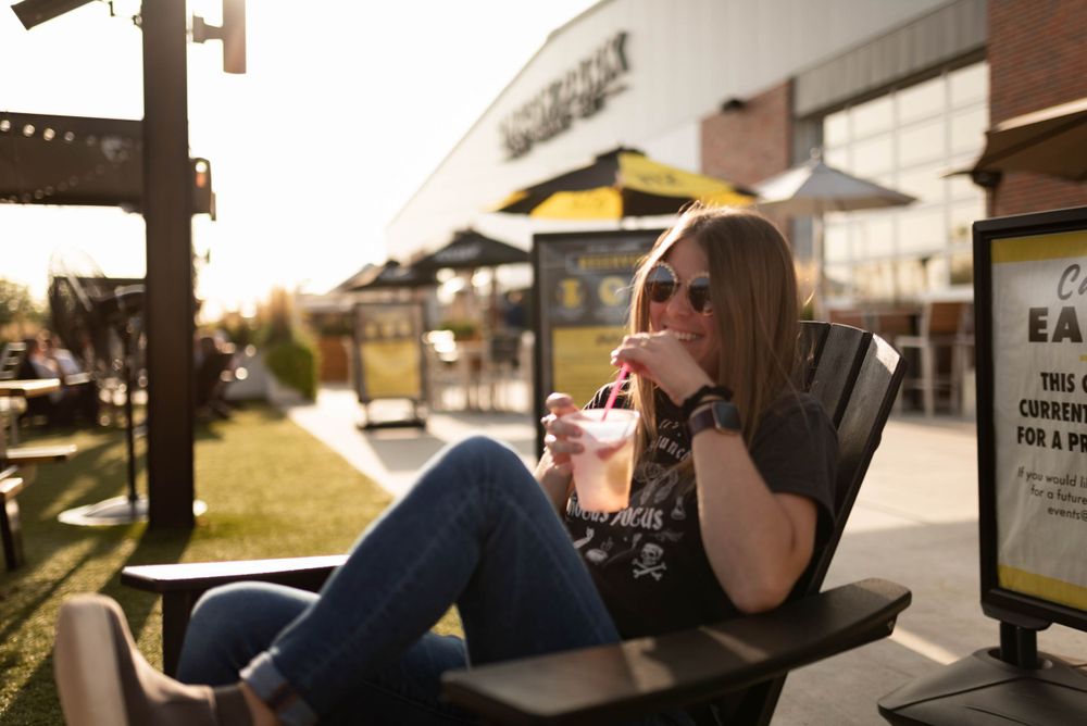self portrait of Iowa Midwest photographer holding a drink & sitting in a chair at SMASH park downtown des moines natural light photography.