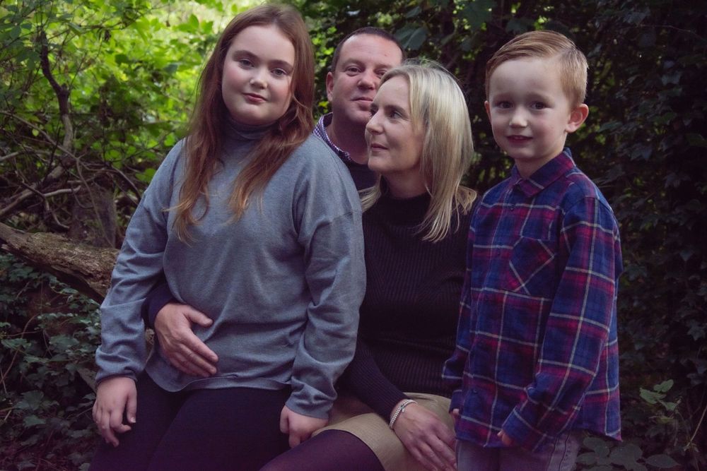 Family of four posed together outdoors wearing casual attire.