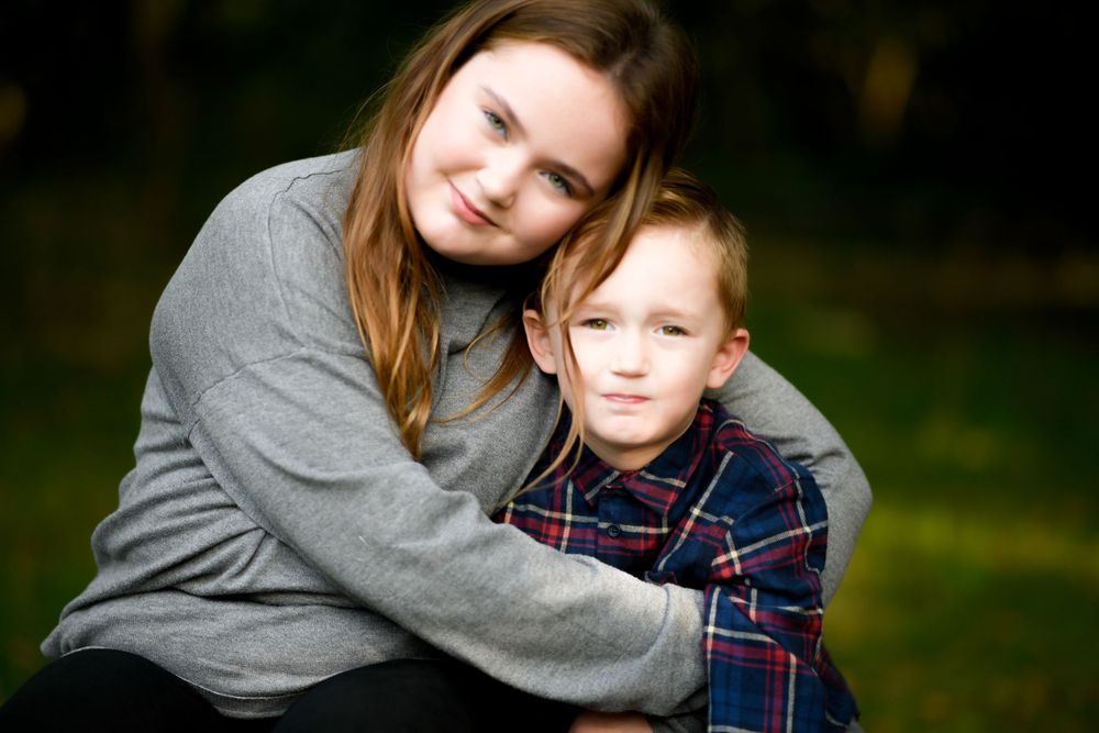 A tender family moment outdoors with a grey sweater and plaid shirt in natural lighting.