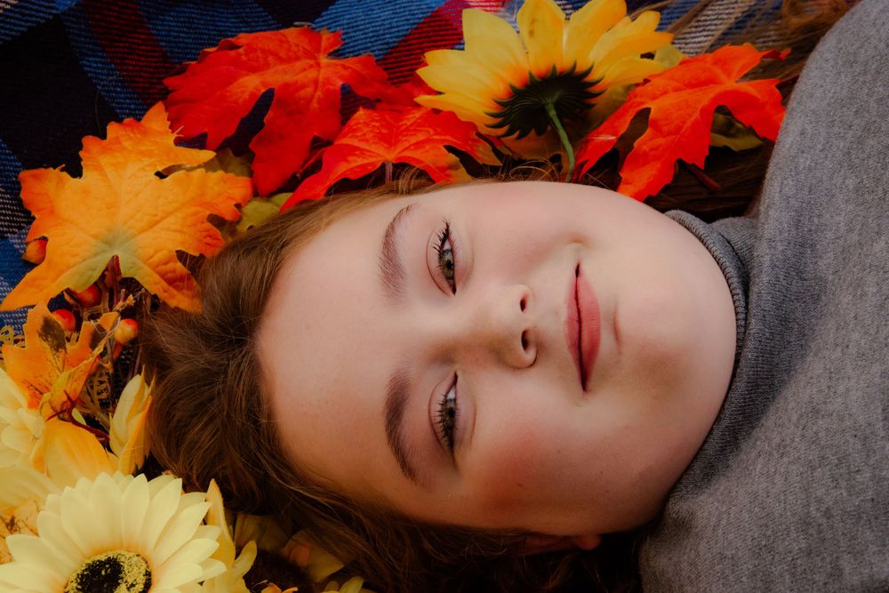Artistic portrait with autumn leaves and sunflowers creating seasonal frame.