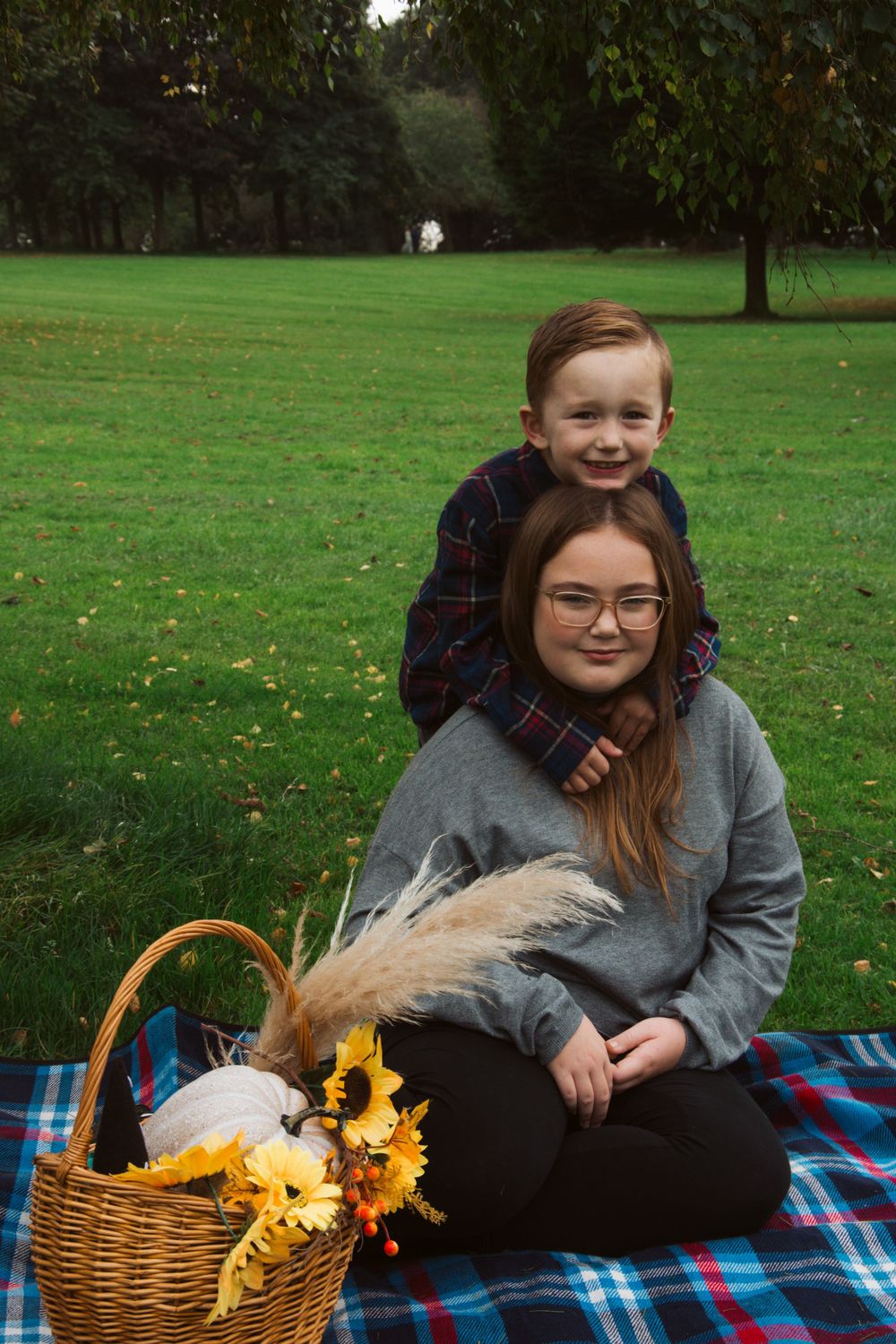 Two people enjoying outdoor picnic with decorative basket of sunflowers and feathers.