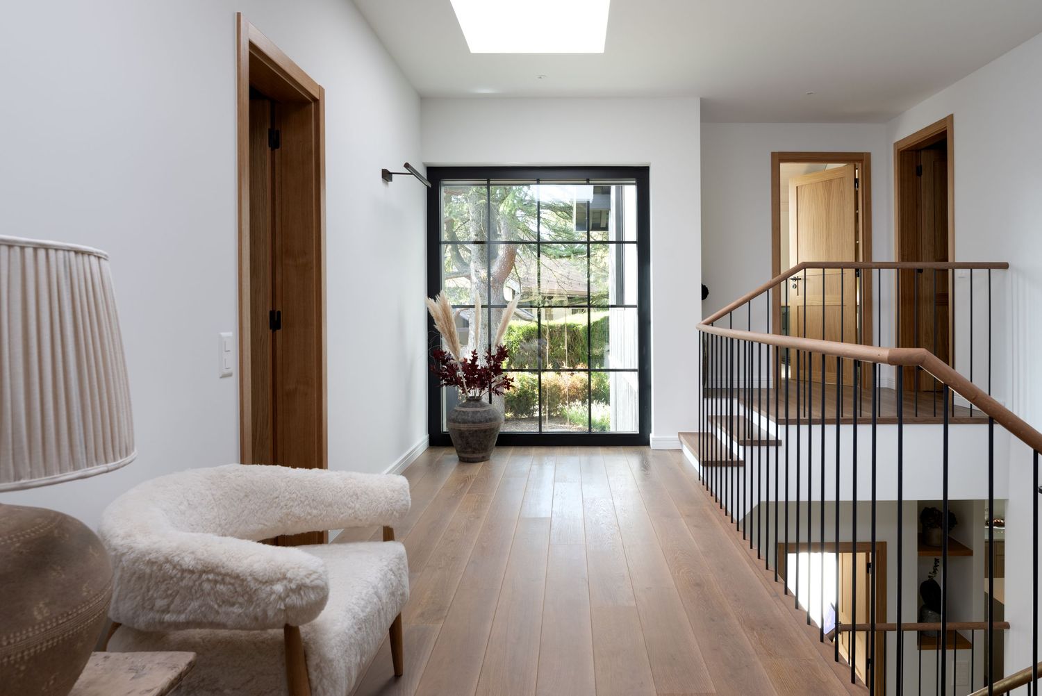 The landing at the top of the stairs; at the far end of the landing is a large window with a garden view