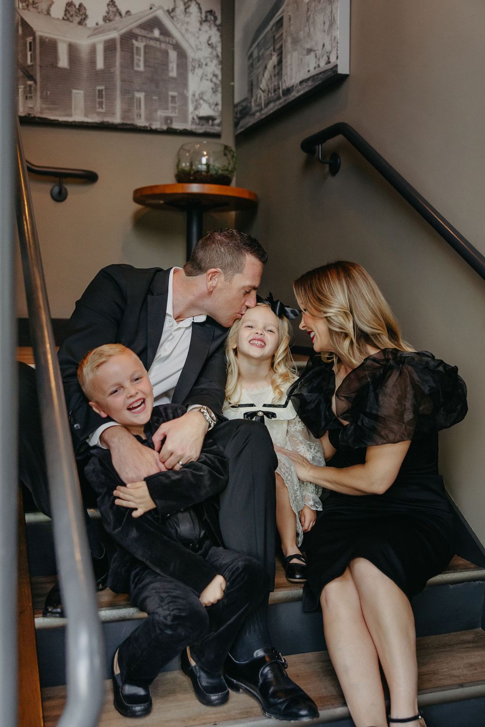 A candid family moment on stairs showing playful interaction and laughter.