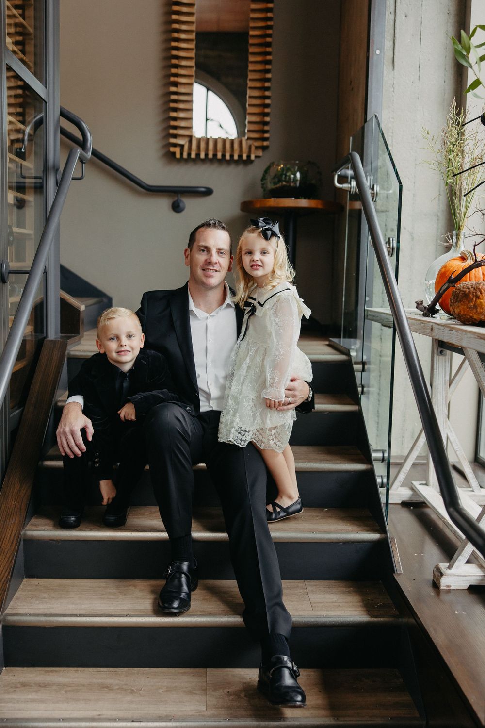 A casual family portrait on modern wooden stairs with industrial design elements.
