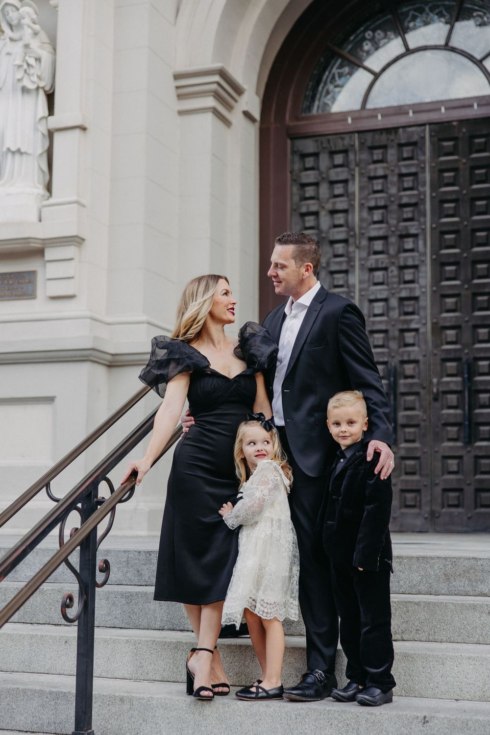 Family of four poses together on stone steps wearing formal attire.