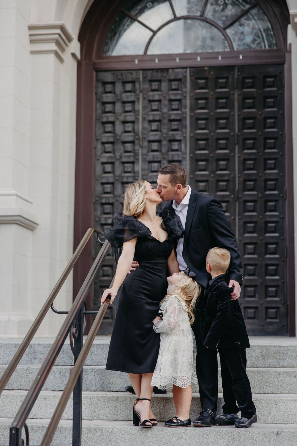 Family shares intimate moment on stone steps during formal photo session.
