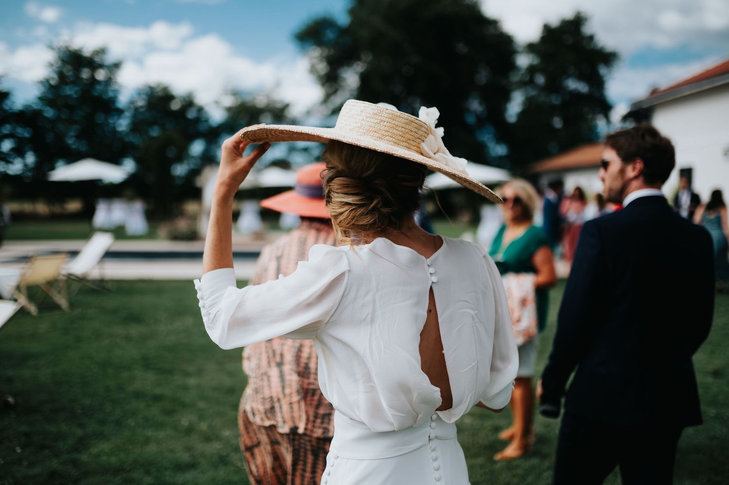 Outdoor wedding celebration with guests under blue summer sky.