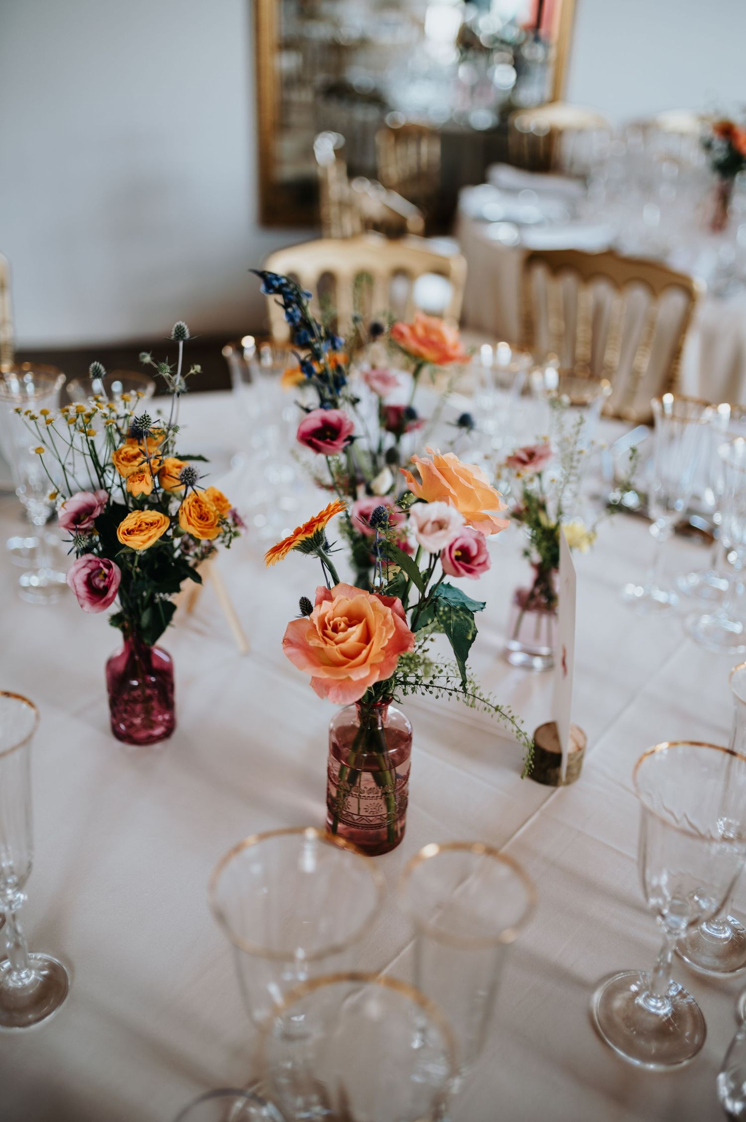 Elegant wedding table setting with colorful floral centerpieces and wine glasses.
