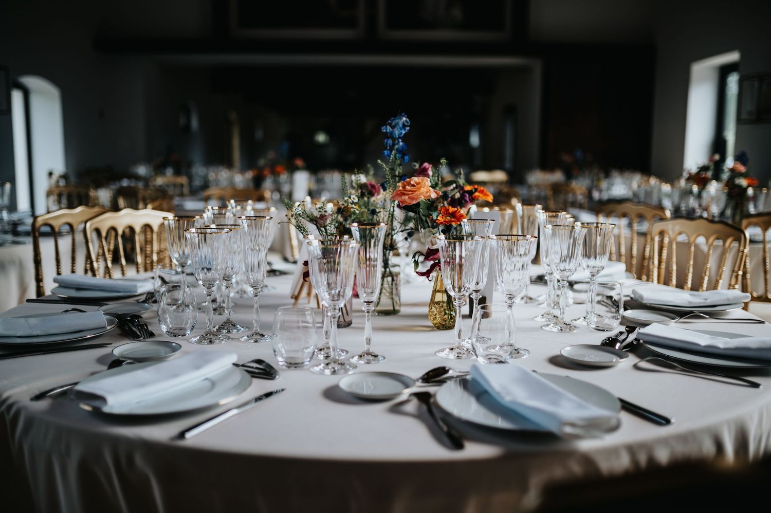 Long wedding reception table with formal place settings and white linens.