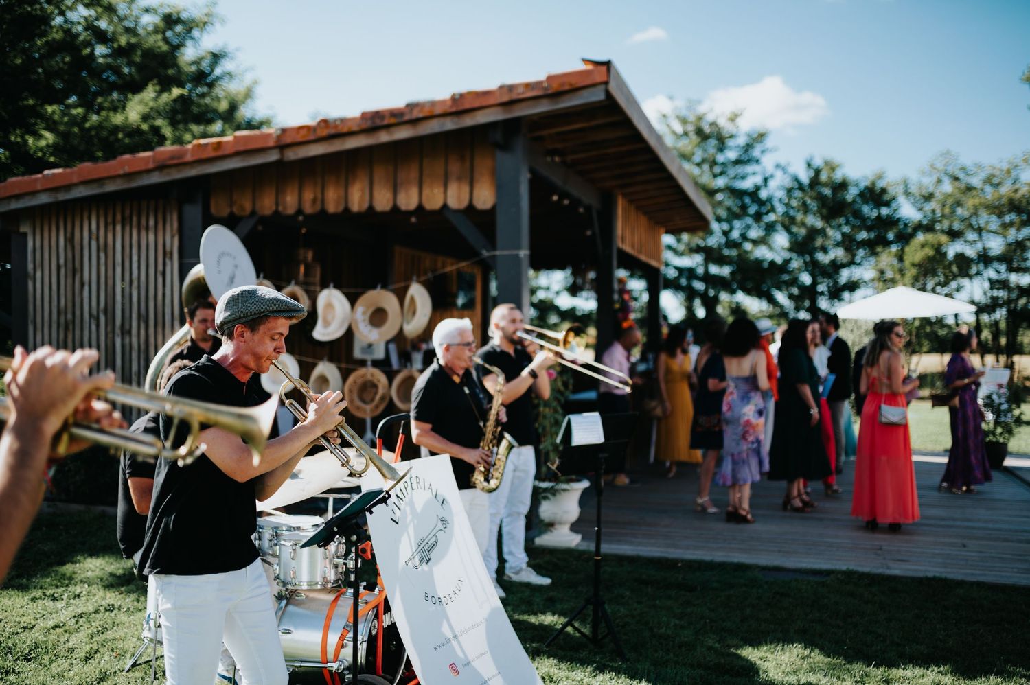 Outdoor wedding venue with wooden pavilion and guests gathering.