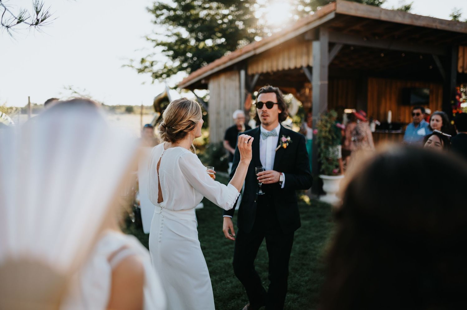 Wedding celebration at a rustic barn venue with guests mingling at sunset.