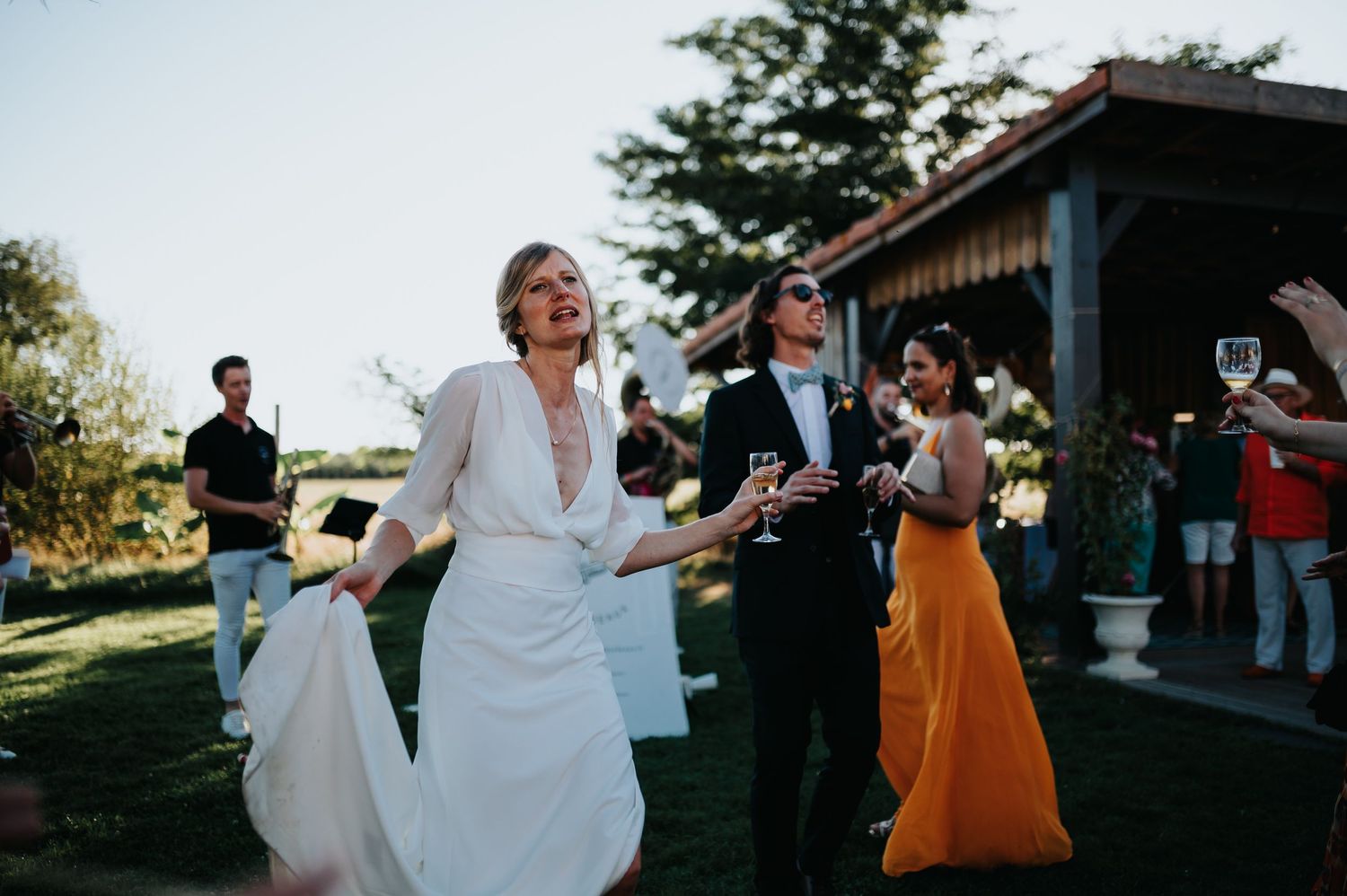 Lively dancing and celebration at an outdoor wedding reception near a rustic building.