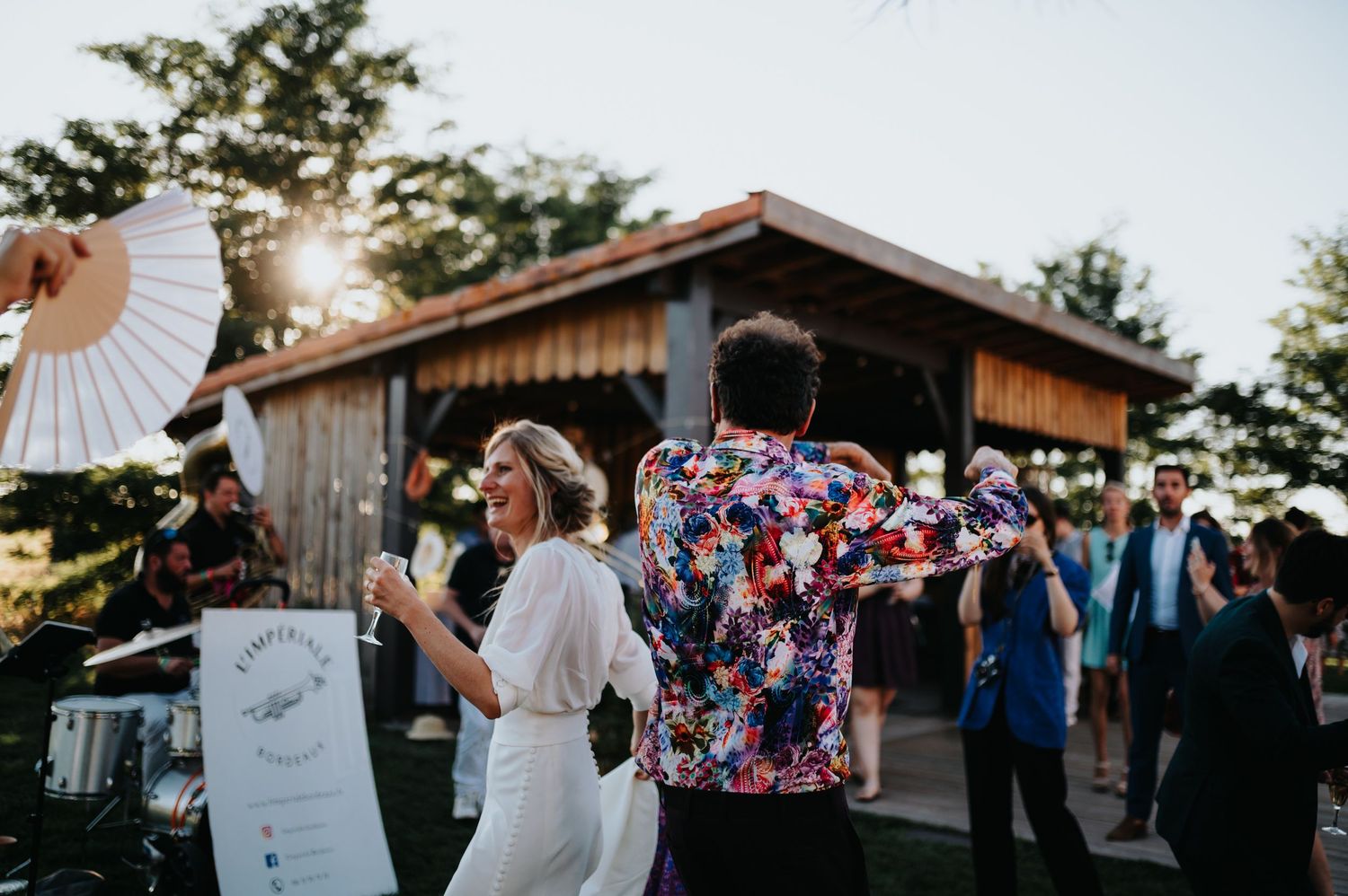 Guests celebrating at an outdoor wedding reception with a rustic barn backdrop.