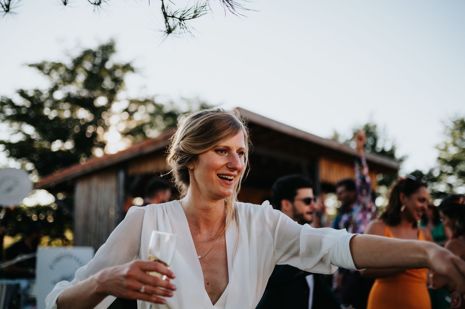 Wedding celebration in full swing at a rustic outdoor venue during golden hour.