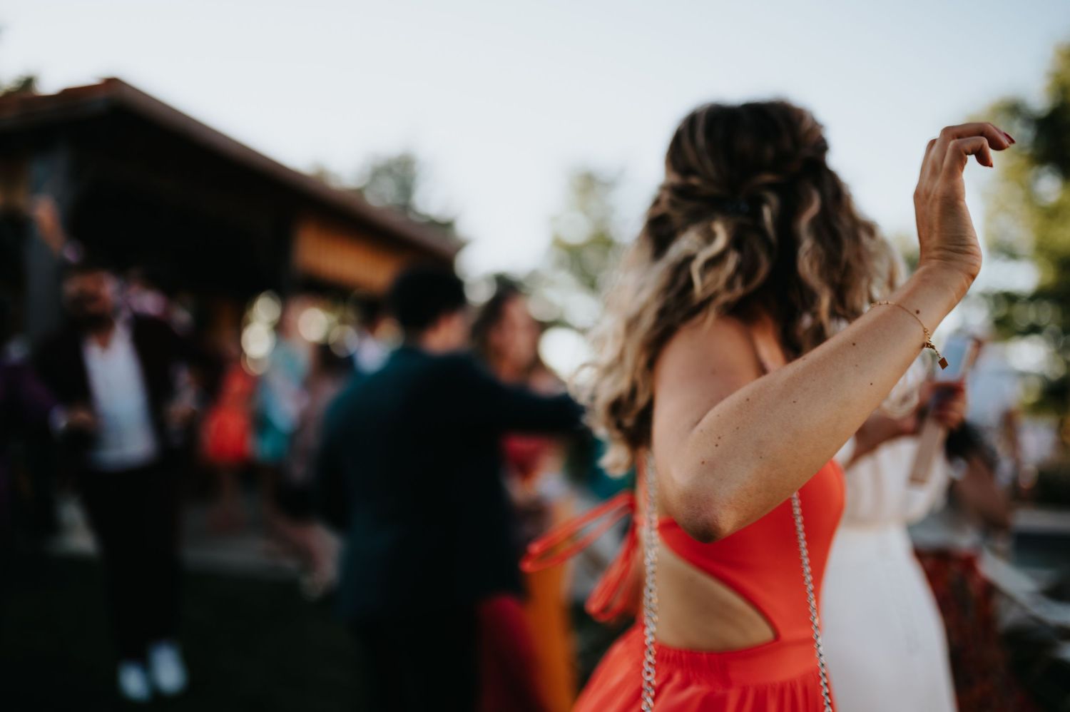People dancing joyfully at an outdoor wedding reception.