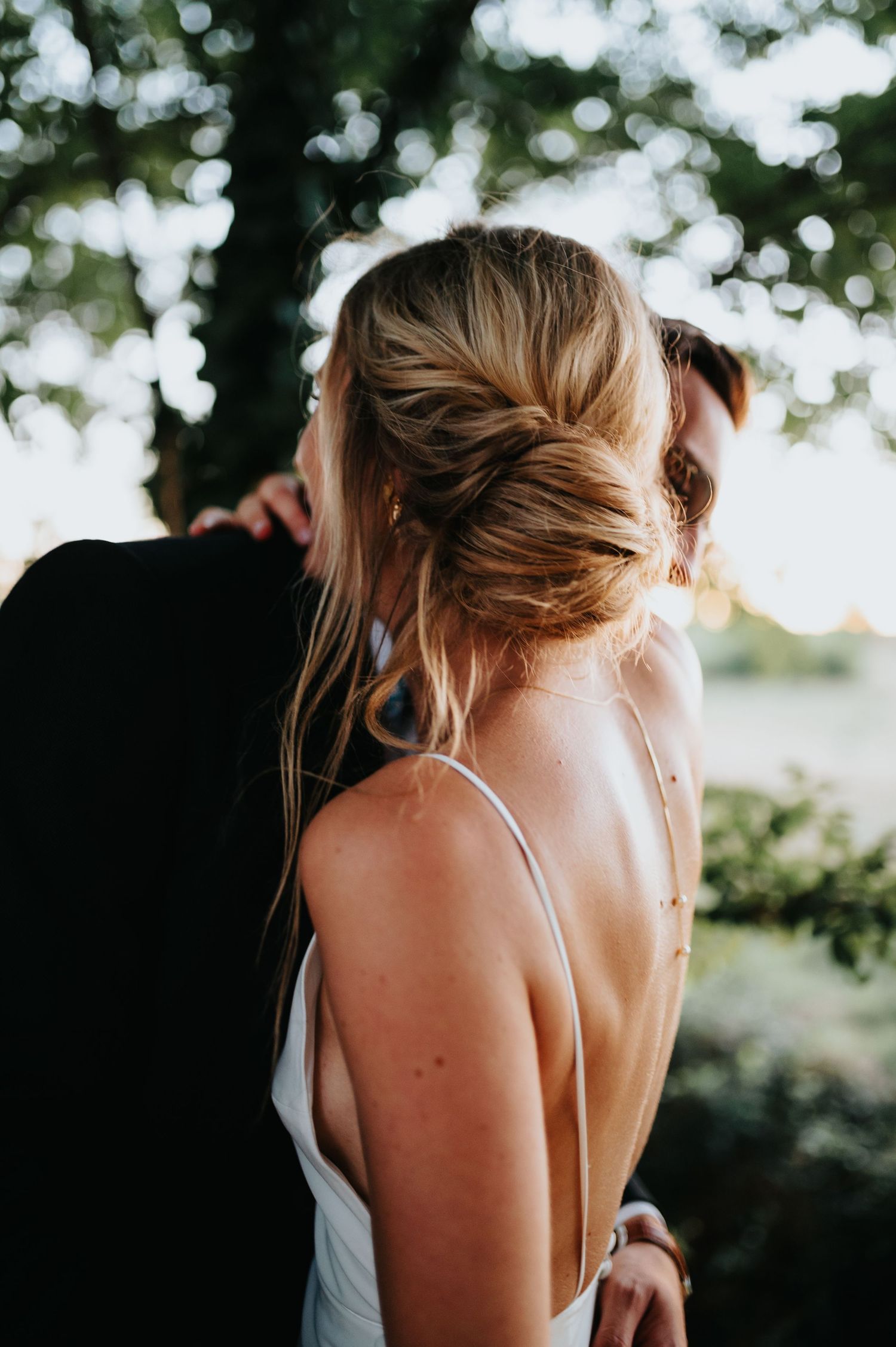 Close-up of an elegant white dress strap and styled hair in natural lighting.