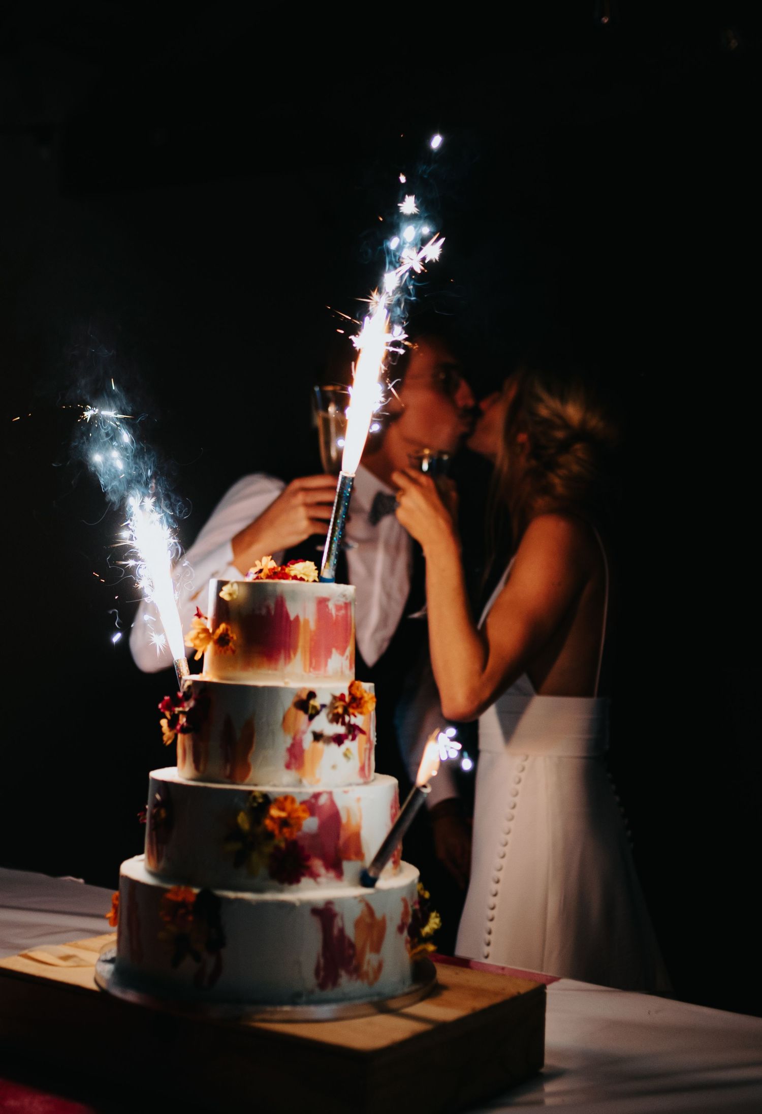 Wedding cake with sparklers creating dramatic lighting effects in the dark.