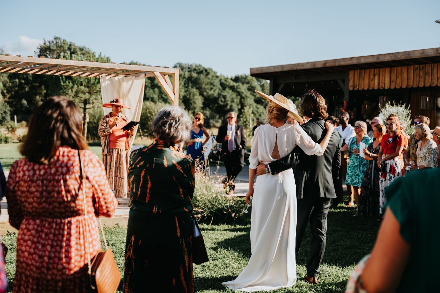 Wedding guests mingle and celebrate at an outdoor reception during golden hour.