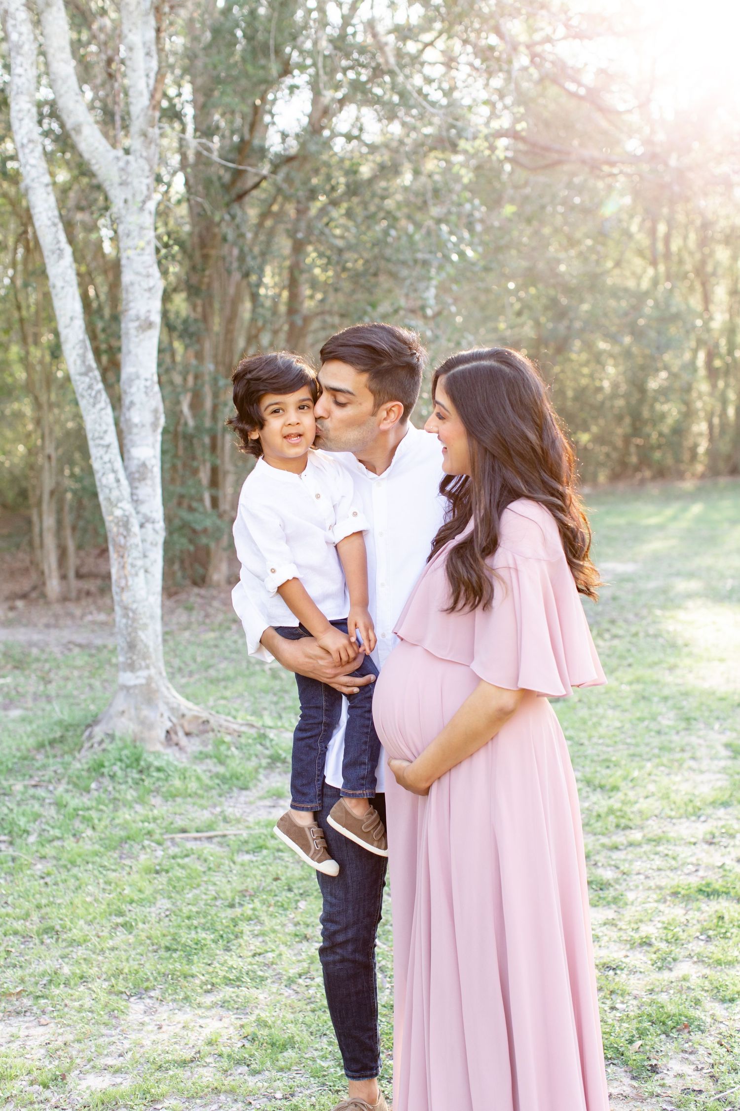 A sweet family moment captured in golden sunlight with birch trees creating a natural backdrop.