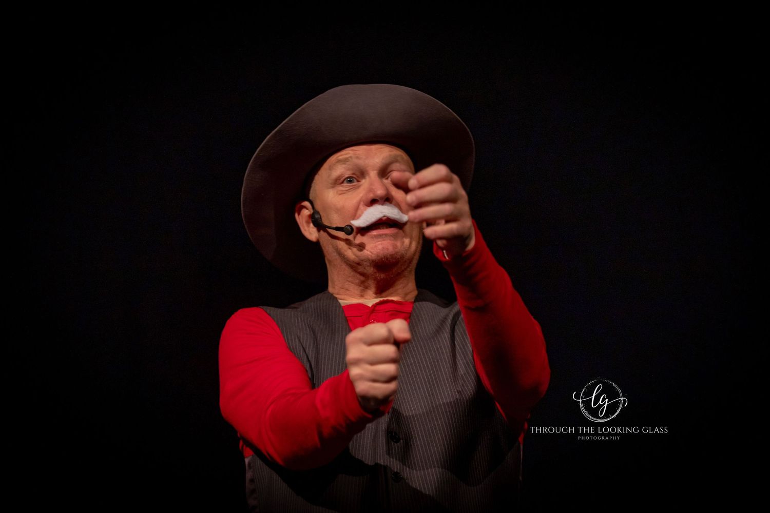 A performer in western wear adjusts their costume during a theatrical production.