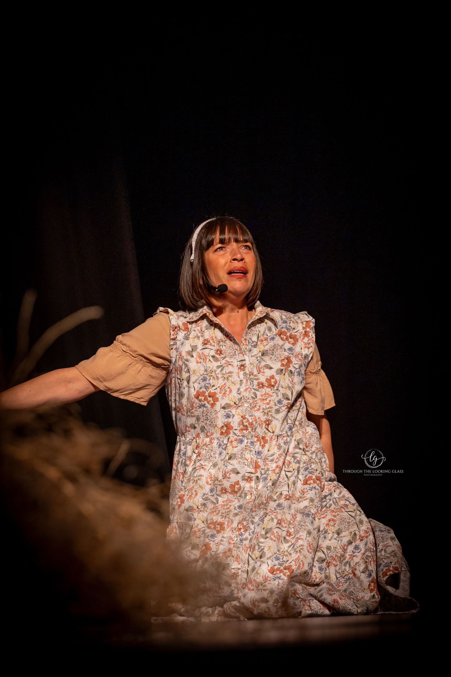 Performer in floral dress and bangs sings passionately during stage performance.