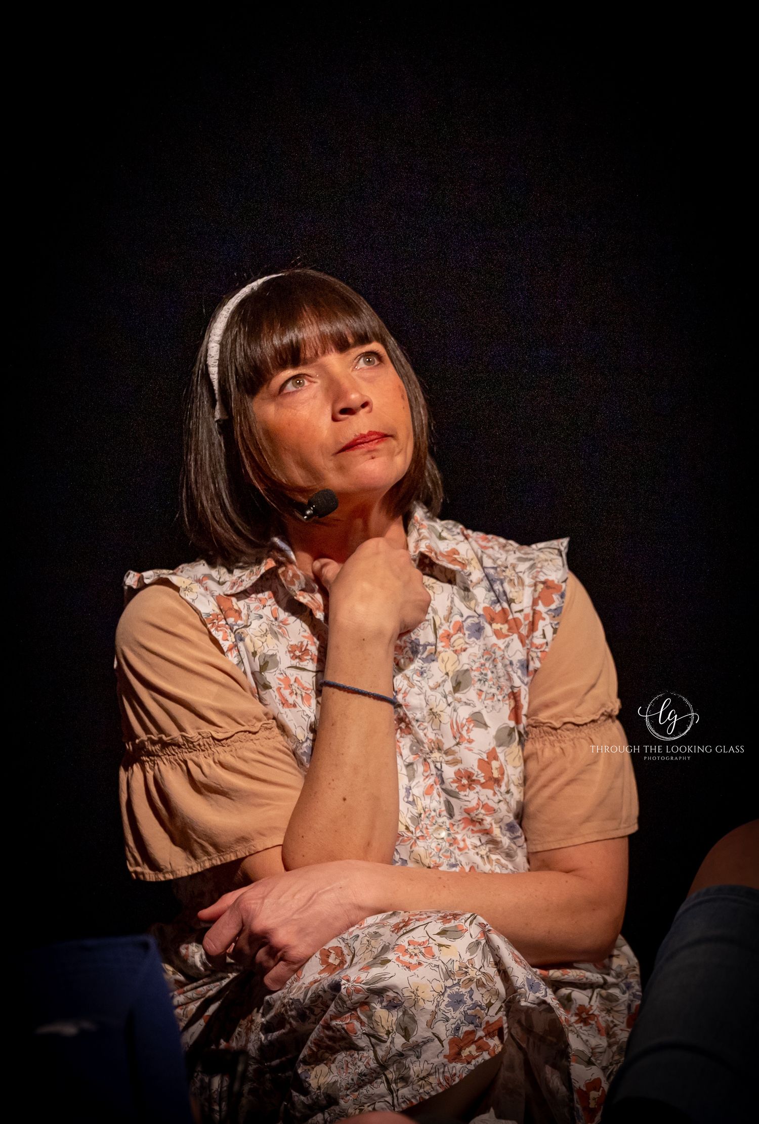 A thoughtful performer in vintage dress poses during a theatrical production.
