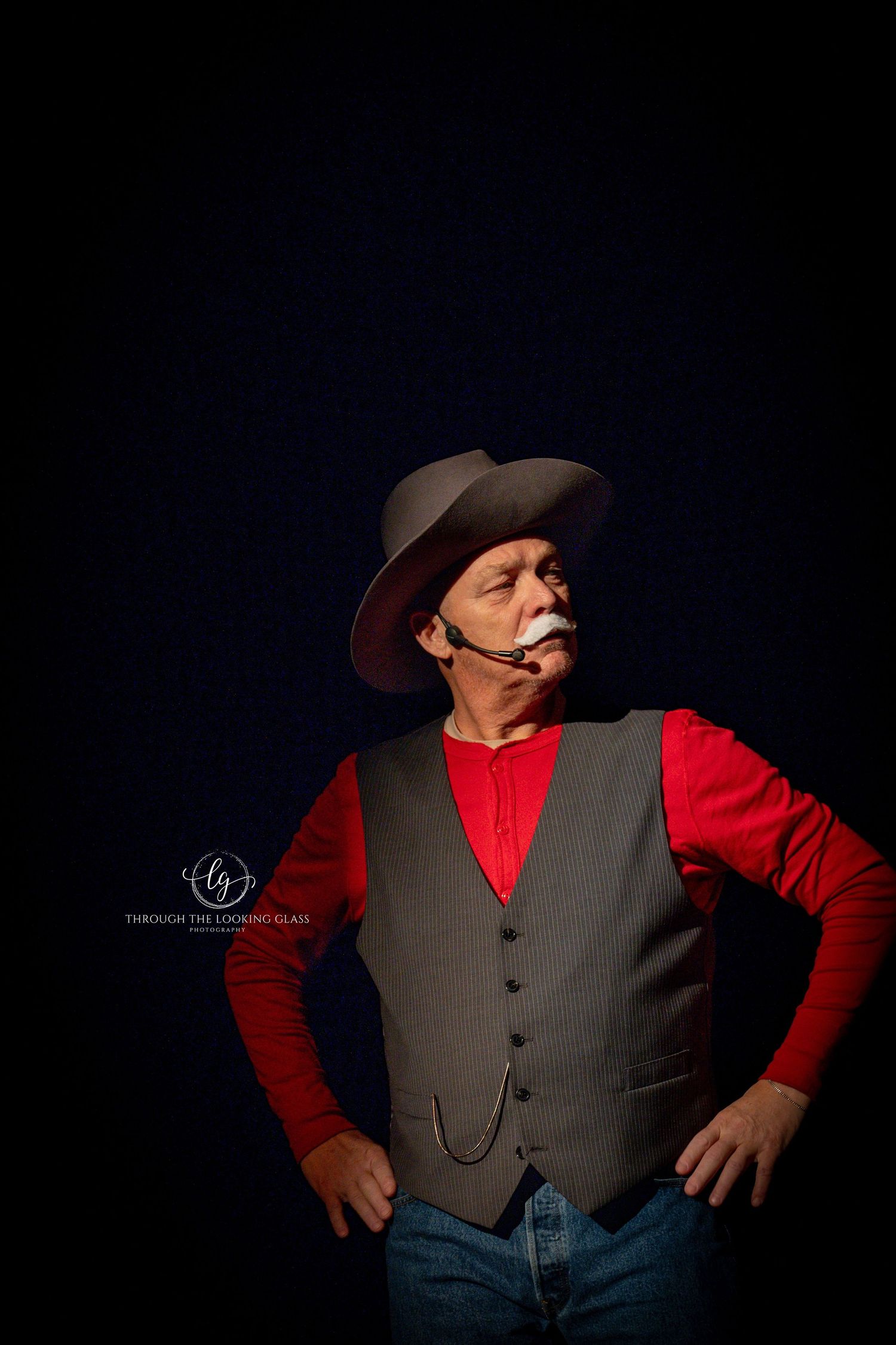 Western character in red shirt and gray vest strikes confident pose against dark background.