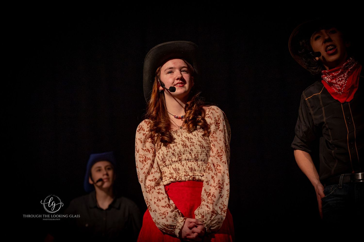 A stage performer in western costume laughs during a theatrical production.