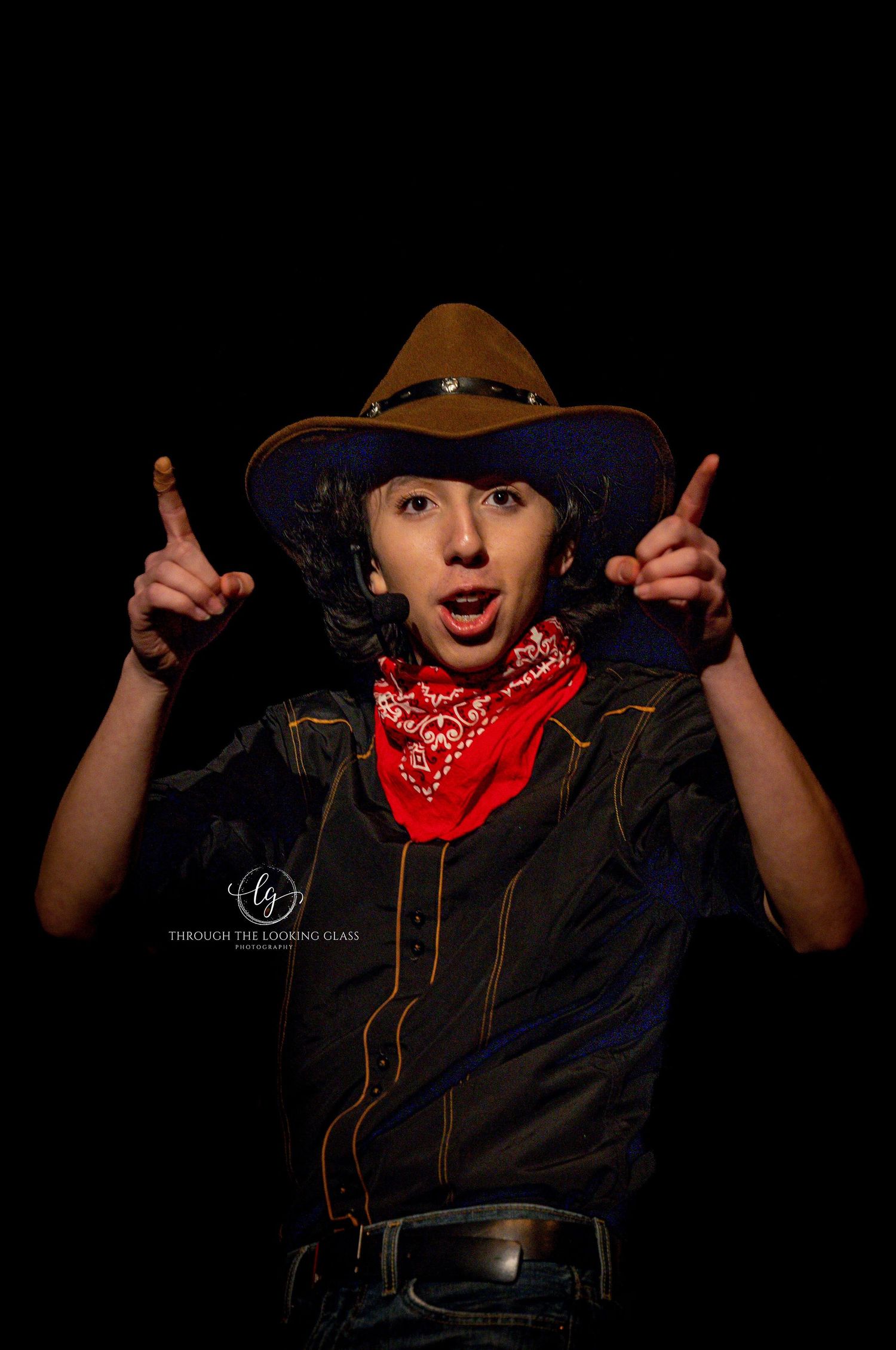 Energetic performer in cowboy attire strikes a playful pose with raised hands.