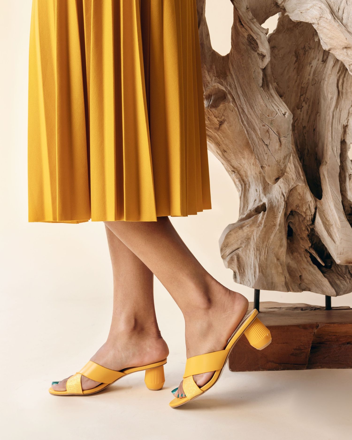 Yellow pleated skirt and matching block heel sandals styled with rustic driftwood decor.