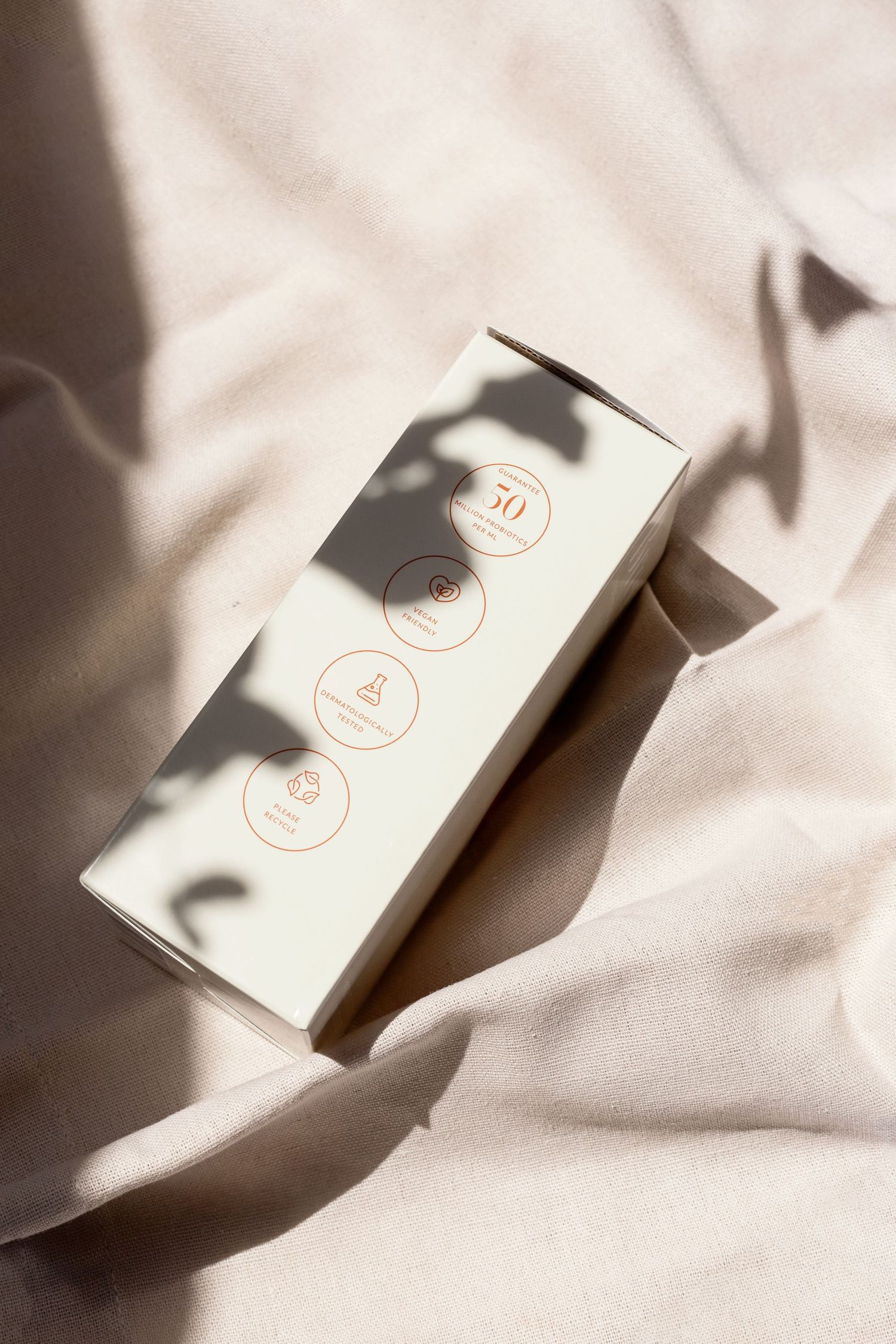 Minimalist white product box with circular icons casting dramatic shadows.